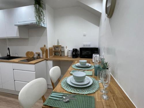 une cuisine avec une table en bois, des assiettes et des verres dans l'établissement Chic Cocon in Rouen, à Rouen