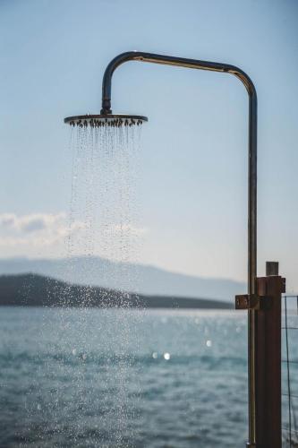 a shower with water dripping from it next to a body of water at blue symphony suites and apartments in Nikiana