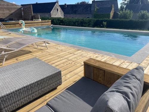 a large swimming pool with a wooden deck and a swimming pool at Grand gîte de Filot in Filot