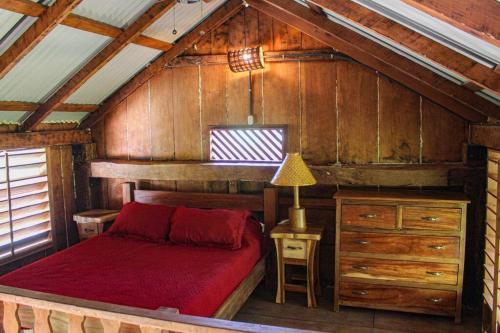 a bedroom with a red bed in a cabin at Surfers Paradise - Cabin next to Yankee Beach in Escamequita