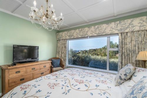 a bedroom with a bed and a large window at Bayview Valley Lodge Bed & Breakfast in Whitianga
