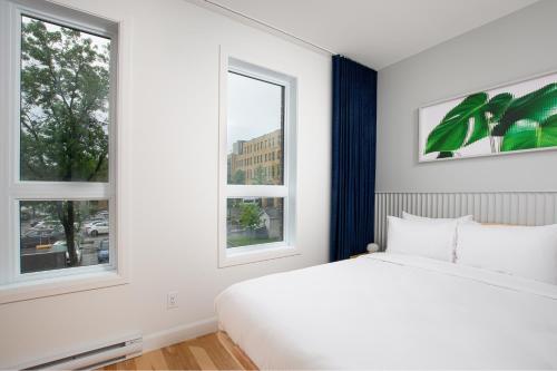 a bedroom with a white bed and two windows at Les Lofts de Vitré - Par Les Lofts Vieux-Québec in Quebec City