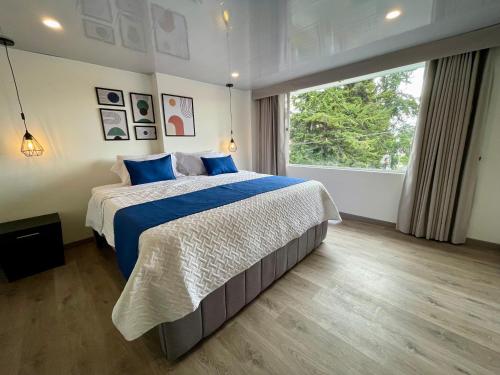 a bedroom with a bed with blue pillows and a window at Hotel Embajada 44 in Bogotá