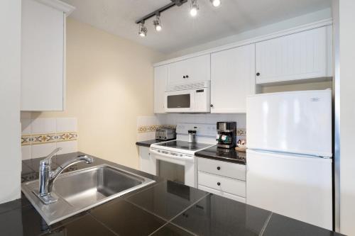 a white kitchen with a sink and a refrigerator at The Aspens by Whiski Jack in Whistler