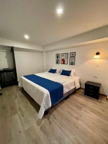 a bedroom with a large bed with a blue blanket at Hotel Embajada 44 in Bogotá