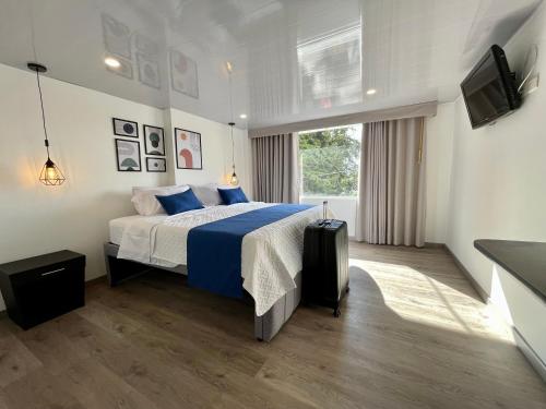 a bedroom with a bed with blue sheets and a television at Hotel Embajada 44 in Bogotá