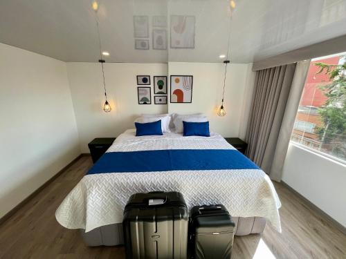 a bedroom with a bed with two suitcases on the floor at Hotel Embajada 44 in Bogotá
