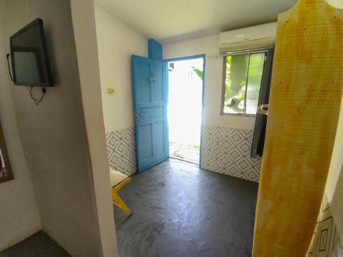Una habitación vacía con una puerta azul y un televisor. en Coliving Porto de Galinhas, en Porto de Galinhas