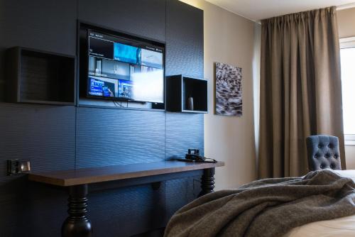 a bedroom with a desk with a tv on the wall at Lapland Hotels Oulu in Oulu