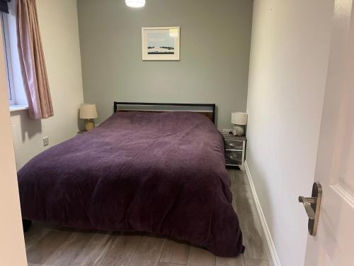 a bedroom with a purple bed and two night stands at The Apartment at Woodside in Stockton-on-Tees