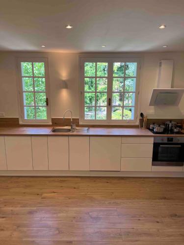a kitchen with white cabinets and two windows at Villa champenoise, La Psière in Courthiézy