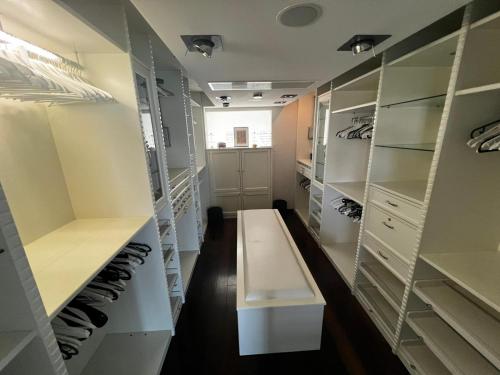 a walk in closet with white cabinets and a bench at Marque De Lago in Bucharest