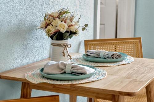a wooden table with two plates and a vase with flowers at The Seashell Suite with Private Balcony and Walk to Beach in Clearwater Beach