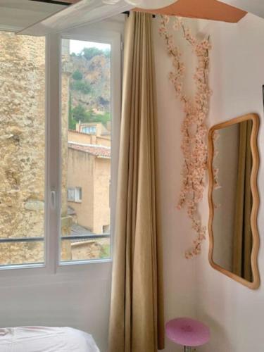 - une chambre avec une fenêtre, un lit et un miroir dans l'établissement Duplex au coeur de Cotignac, à Cotignac