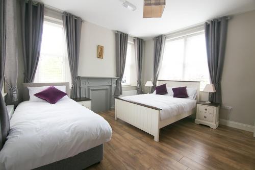 two beds in a bedroom with two windows at Millmasters House B&B at the Riverbank Restaurant in Drumahayre