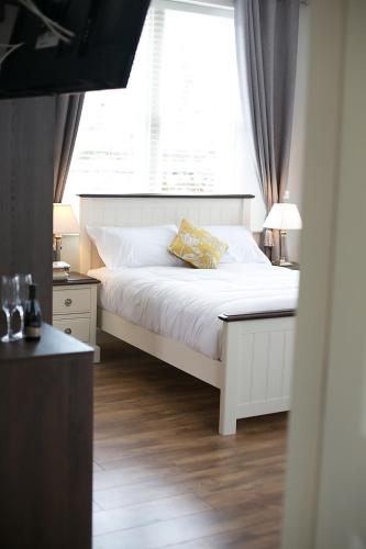 a bedroom with a white bed and a window at Millmasters House B&B at the Riverbank Restaurant in Drumahayre