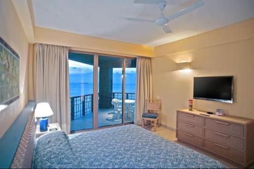 ein Schlafzimmer mit Bett und Fernseher und Balkon in der Unterkunft Zuana Beach Resort -Semana 37 in Playa Dormida