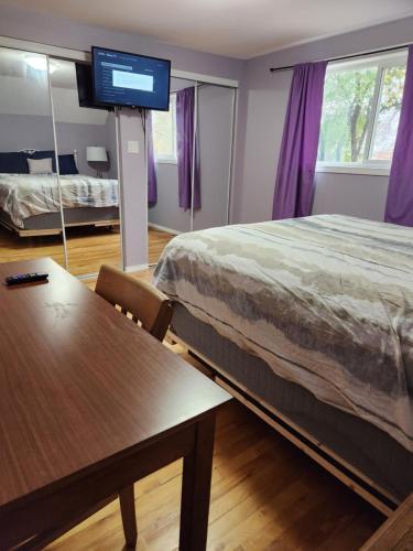 a bedroom with a bed and a table and a tv at Gateway Place in Winnipeg