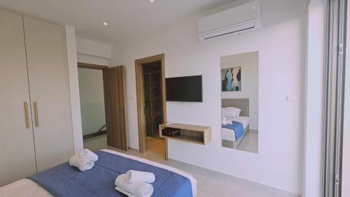 a bedroom with a blue bed and a television at STAY Oasis Luxury Villas in Ayia Napa