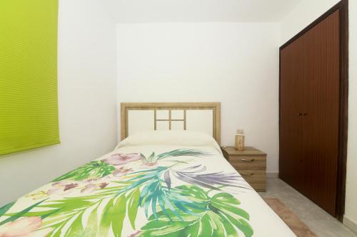 a bedroom with a bed with a colorful blanket on it at Apartamento O Cruceiro in A Pobra do Caramiñal