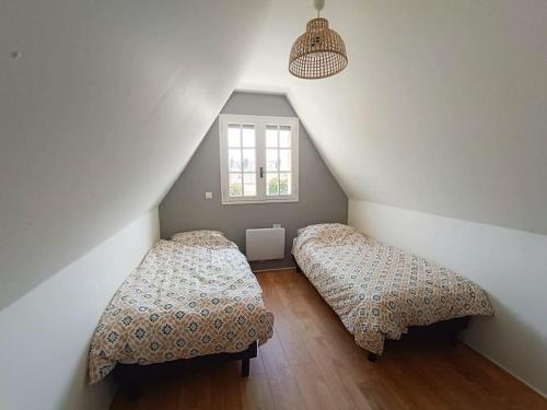 une chambre mansardée avec deux lits et une fenêtre dans l'établissement La Dinannaise, à Étel