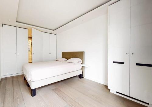 une chambre blanche avec un lit et des armoires blanches dans l'établissement Appartement proche Étoile, à Paris