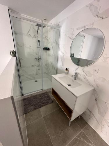 une salle de bain avec une douche, un lavabo et un miroir dans l'établissement Appartement centre-ville Bedarieux, à Bédarieux
