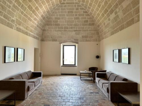 a living room with couches and a brick wall at Relais Histò San Pietro Sul Mar Piccolo in Taranto