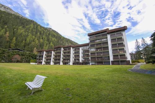 un banc blanc assis dans l'herbe devant un bâtiment dans l'établissement Résidence Grands Montets 524 - Happy Rentals, à Chamonix-Mont-Blanc