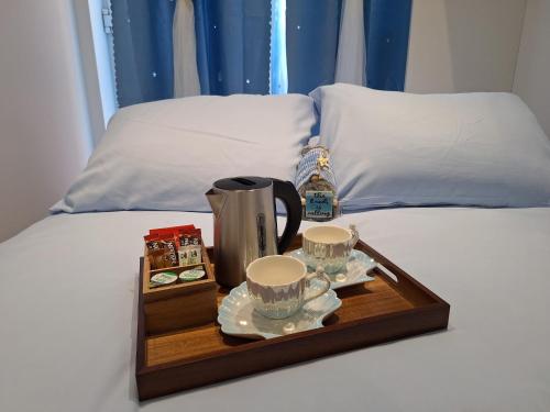 a tray with a coffee maker and two cups on a bed at Sunny Waves in Northampton