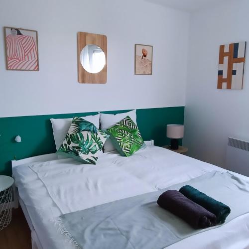 - un lit blanc avec des oreillers verts et blancs dans l'établissement Lush Fresh Home in Paris near Stade de France, à Saint-Denis