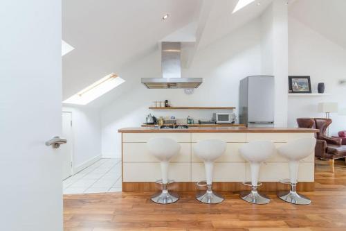 a kitchen with white walls and a counter with stools at 4 stars Rating Tourist board certified Spacious penthouse Apartment in Belfast