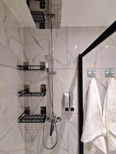 a shower in a bathroom with white marble walls at Sunny Waves in Northampton