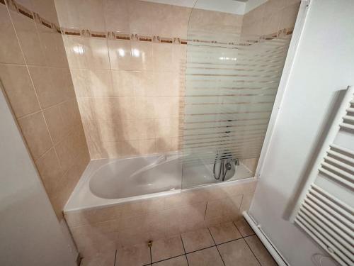 une salle de bain avec baignoire et sol carrelé dans l'établissement Studio Cosy proche de Disney, à Magny-le-Hongre