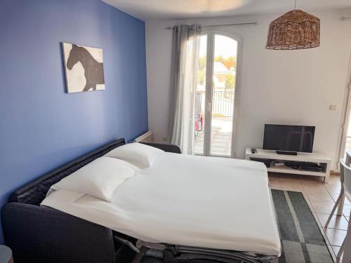 une chambre avec un lit blanc et une télévision dans l'établissement Studio Cosy proche de Disney, à Magny-le-Hongre