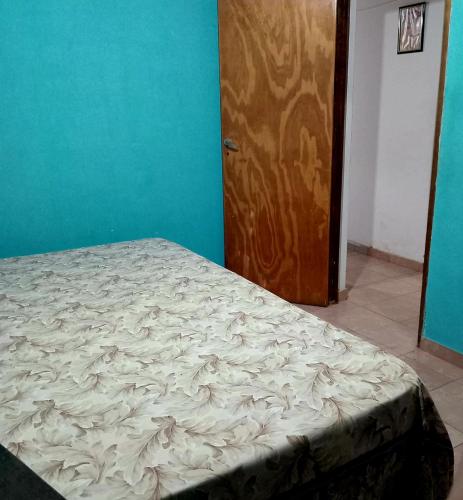 an empty bed in a room with a door at Casa Marconi in Posadas