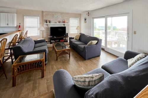 a living room with couches and a tv and a kitchen at No Regrets Up in Emerald Isle