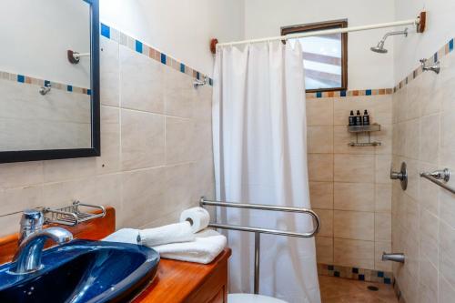 Un baño con un lavabo azul y una ducha. en Casa Wow, en Quepos