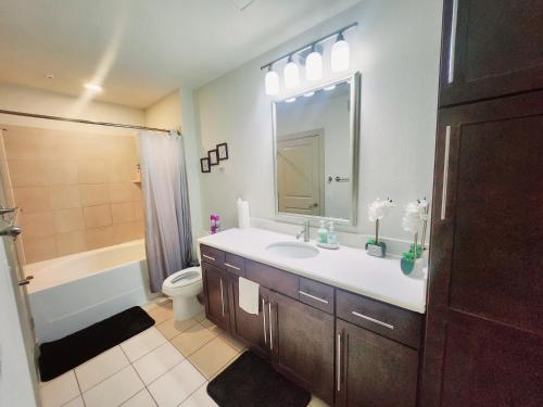 Un baño con lavabo, inodoro y espejo. en Belle Maison near Medical Center NRG Stadium, en Houston