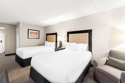 a hotel room with two beds and a couch at Sonesta Essential Atlantic City West in Egg Harbor Township
