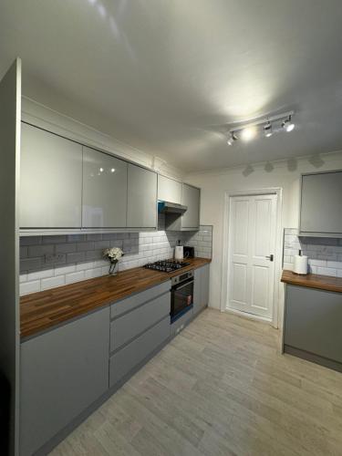 una cocina con armarios blancos y encimeras de madera en QD Homes, en Kent