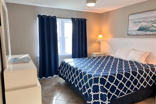 a bedroom with a bed with blue curtains and a window at Perdido Dunes #27 in Orange Beach