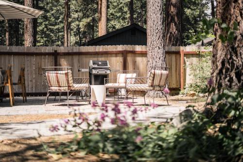 a grill and chairs in a backyard with a fence at Troubadour's Landing in Kings Beach