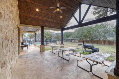 a patio with benches and tables and a ceiling fan at Happy Hour in Concan