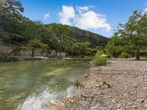 a river with a rocky shore with trees in the background at She's Like Texas in Concan