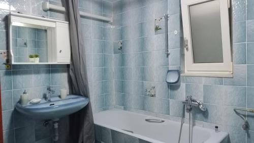 a blue tiled bathroom with a sink and a mirror at Gamila Sunrise in Konitsa