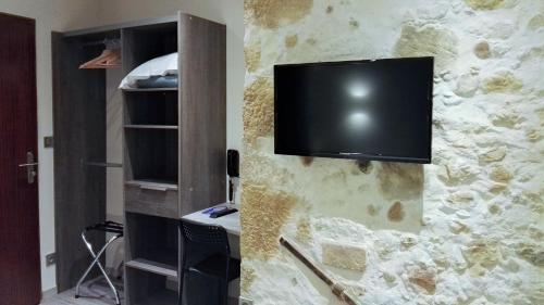 a tv hanging on a stone wall with a room at Hotel de la Couronne in Aix-les-Bains