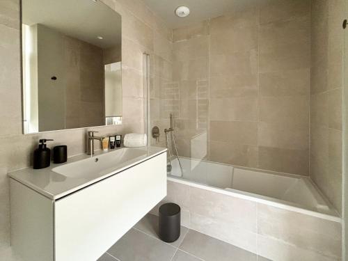 La salle de bains est pourvue d'une baignoire blanche, d'un lavabo et d'une baignoire. dans l'établissement PORS-MABO T3, Luxury 2 Bedroom Apartment with Sea, à Trébeurden