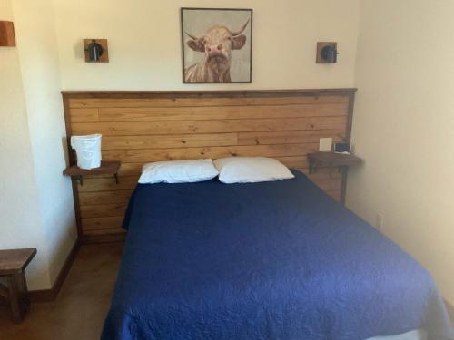 a bedroom with a blue bed with a cow picture on the wall at Double L River House in Concan