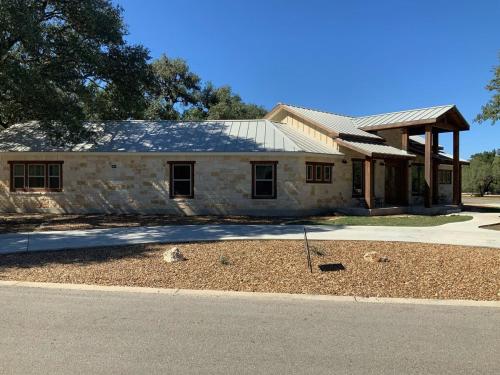 a large stone house with a gambrel roof at Double L River House in Concan